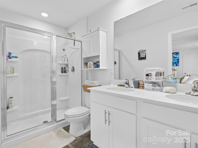 bathroom featuring vanity, toilet, and a shower with shower door