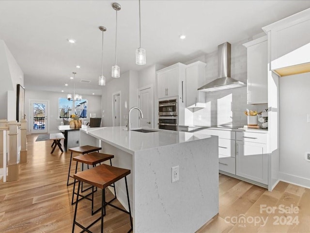 kitchen with white cabinets, sink, and wall chimney exhaust hood