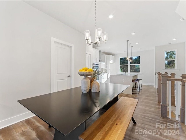 dining space featuring a chandelier, light wood-type flooring, and sink