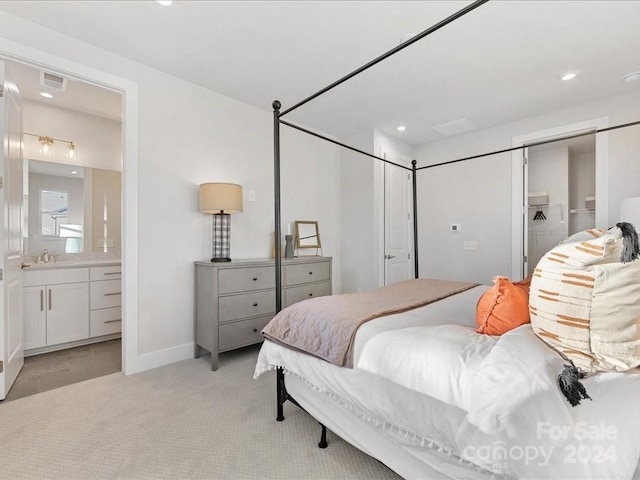 carpeted bedroom featuring connected bathroom and sink