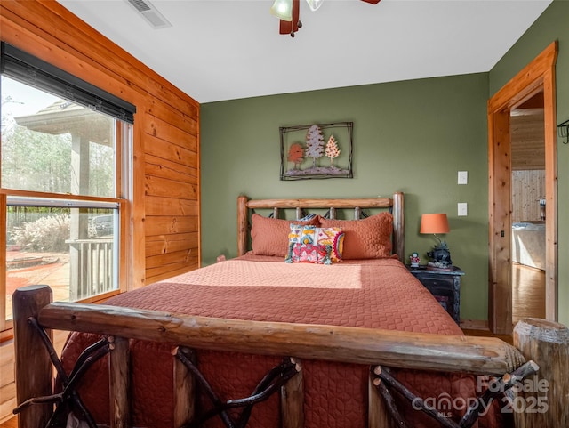 bedroom with ceiling fan and wooden walls