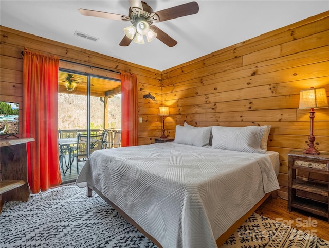 bedroom featuring access to exterior, ceiling fan, and wood walls