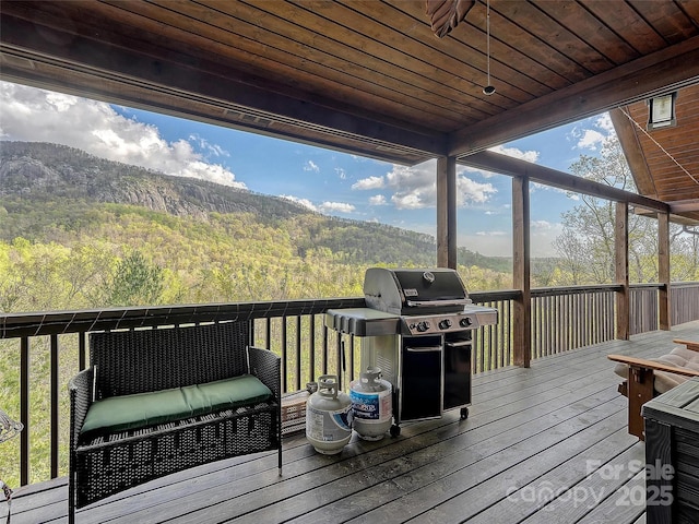 wooden terrace featuring area for grilling, a forest view, and a mountain view