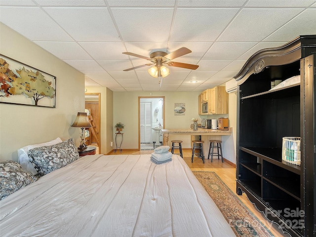 bedroom featuring a paneled ceiling, light wood finished floors, and ensuite bathroom
