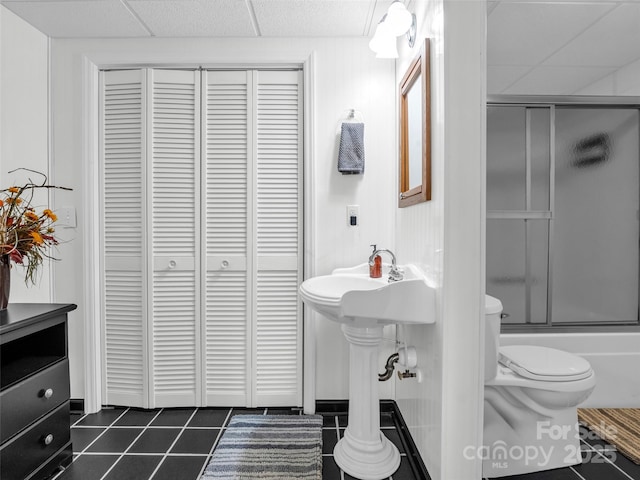 full bathroom with toilet, tile patterned flooring, a closet, and a paneled ceiling