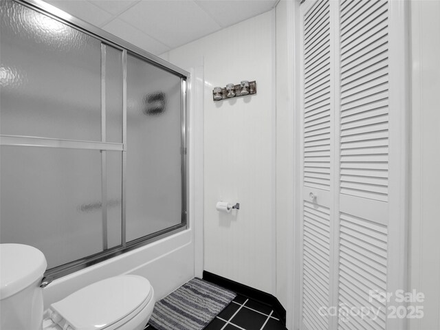 full bath with toilet, tile patterned flooring, a closet, and combined bath / shower with glass door