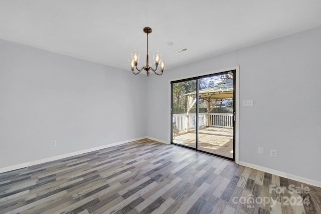 spare room featuring hardwood / wood-style flooring and an inviting chandelier