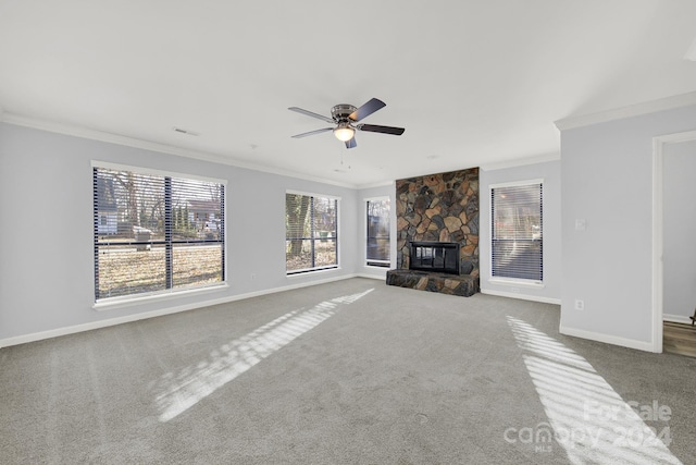 unfurnished living room featuring carpet, a stone fireplace, ceiling fan, and crown molding