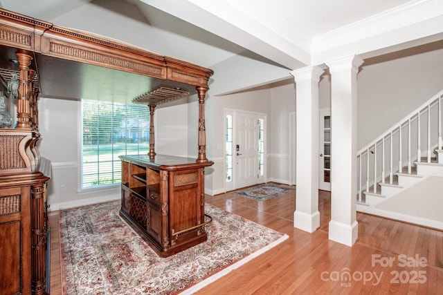 entryway featuring crown molding, light hardwood / wood-style flooring, and ornate columns