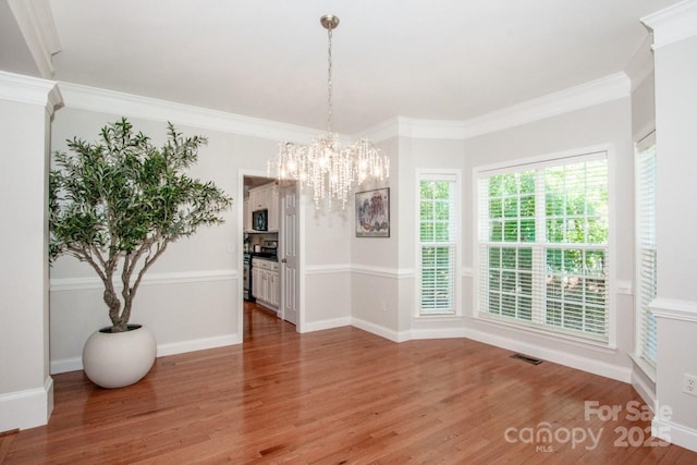 dining space with ornamental molding, hardwood / wood-style floors, and a notable chandelier