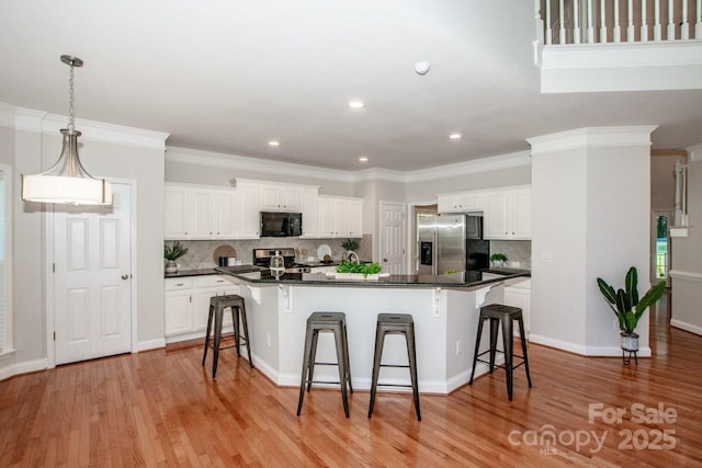 kitchen with appliances with stainless steel finishes, a breakfast bar area, and white cabinets