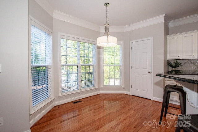 dining space featuring ornamental molding and light wood-type flooring