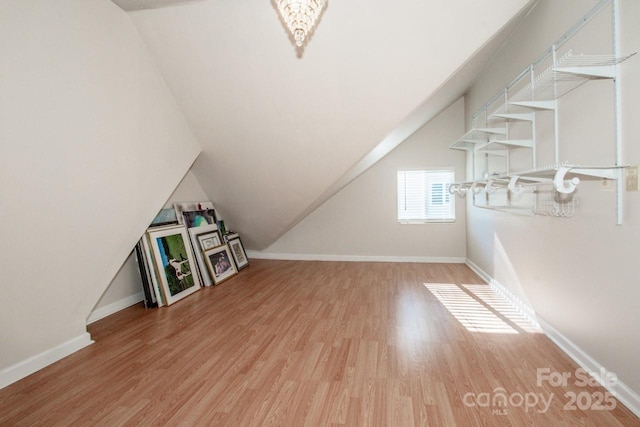 additional living space with vaulted ceiling and light hardwood / wood-style floors