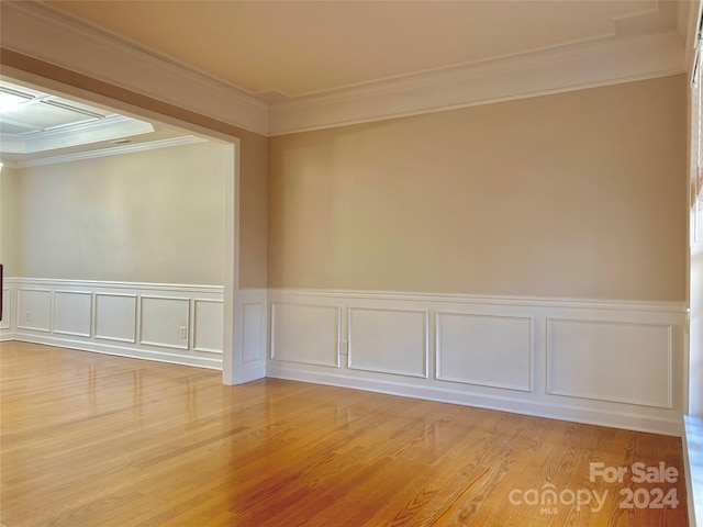 empty room with hardwood / wood-style floors and crown molding