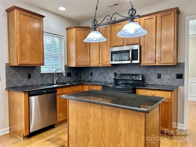 kitchen with a center island, backsplash, light hardwood / wood-style flooring, decorative light fixtures, and stainless steel appliances