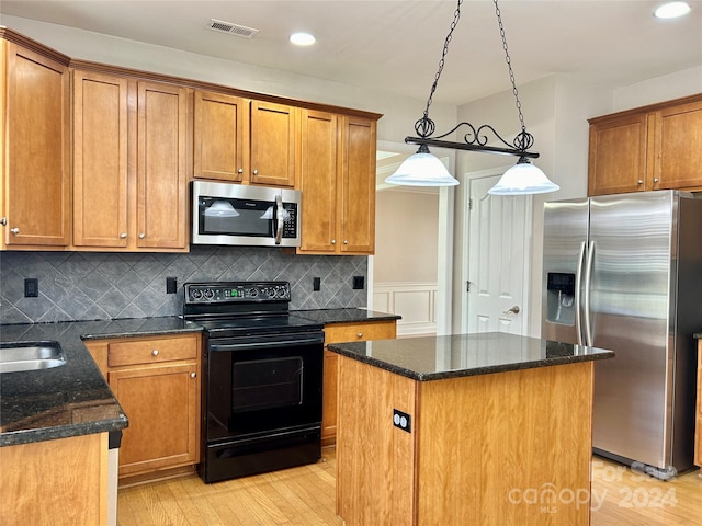 kitchen featuring pendant lighting, light hardwood / wood-style flooring, appliances with stainless steel finishes, tasteful backsplash, and a kitchen island