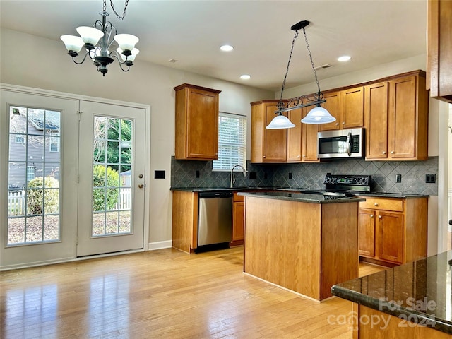 kitchen with a center island, stainless steel appliances, hanging light fixtures, an inviting chandelier, and light wood-type flooring