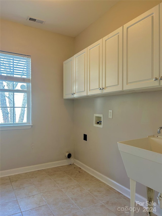 laundry area featuring sink, light tile patterned flooring, cabinets, and washer hookup