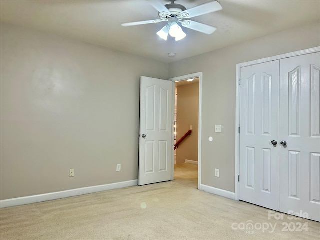 unfurnished bedroom with ceiling fan, light colored carpet, and a closet