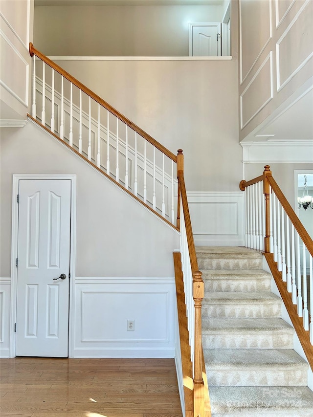 stairway featuring hardwood / wood-style flooring and a notable chandelier