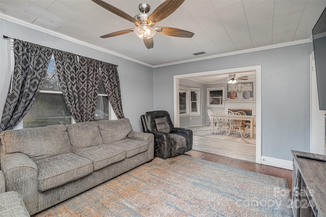 living room featuring ceiling fan, wood-type flooring, and ornamental molding