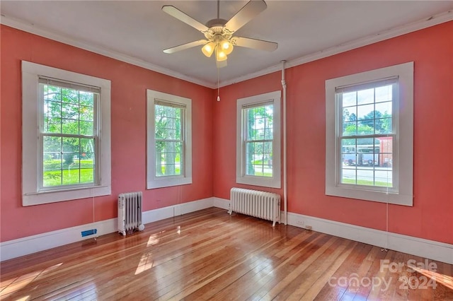 spare room featuring radiator, plenty of natural light, and light wood-type flooring