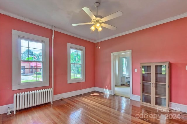 spare room featuring radiator heating unit, light hardwood / wood-style floors, ceiling fan, and crown molding