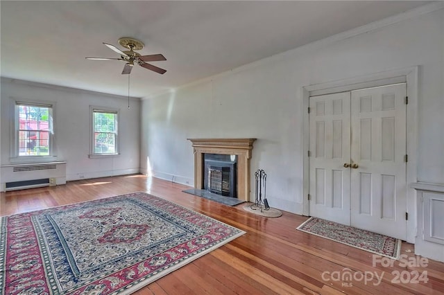 unfurnished living room with ceiling fan, radiator heating unit, and hardwood / wood-style floors