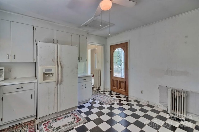 kitchen featuring white refrigerator with ice dispenser, white cabinetry, and radiator