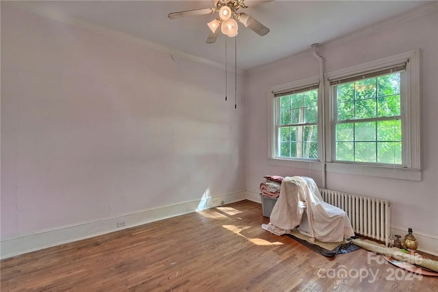 spare room with ornamental molding, radiator heating unit, a healthy amount of sunlight, and hardwood / wood-style flooring