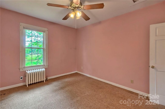 carpeted spare room with radiator heating unit and ceiling fan