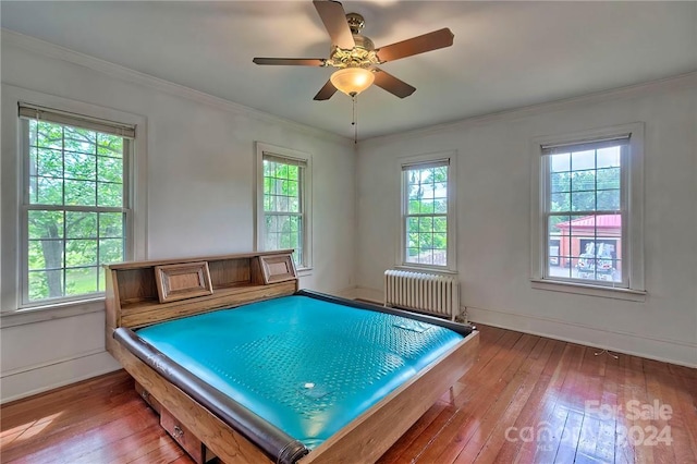 interior space featuring wood-type flooring, radiator, ornamental molding, and ceiling fan