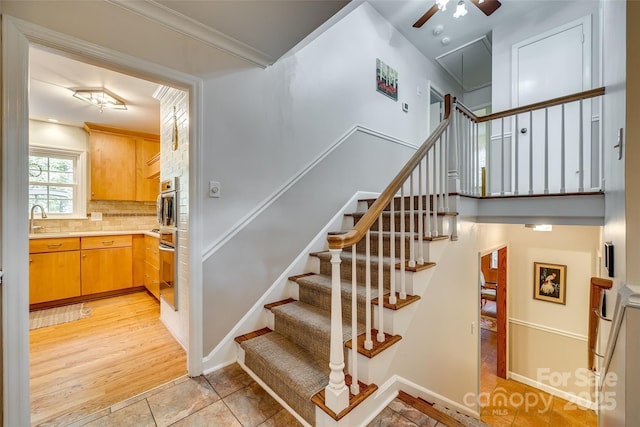 stairs featuring tile patterned flooring, ornamental molding, and sink