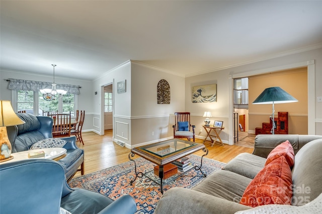 living room with a notable chandelier, light hardwood / wood-style floors, and crown molding