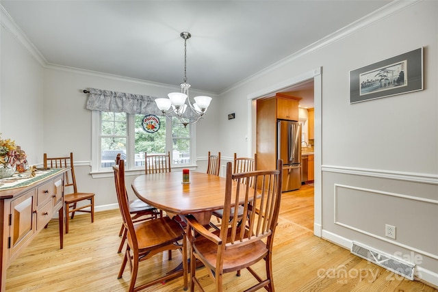 dining space with light wood-type flooring, ornamental molding, and a chandelier