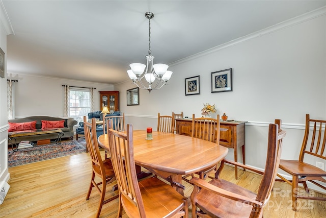 dining room with light wood-type flooring, crown molding, and an inviting chandelier