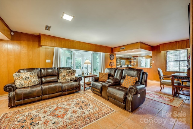 living room with tile patterned flooring, a wealth of natural light, and wooden walls