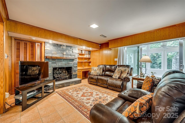 tiled living room featuring a fireplace, built in shelves, and wood walls