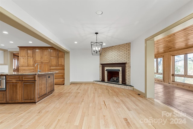 kitchen with decorative light fixtures, light stone counters, a fireplace, and light hardwood / wood-style flooring