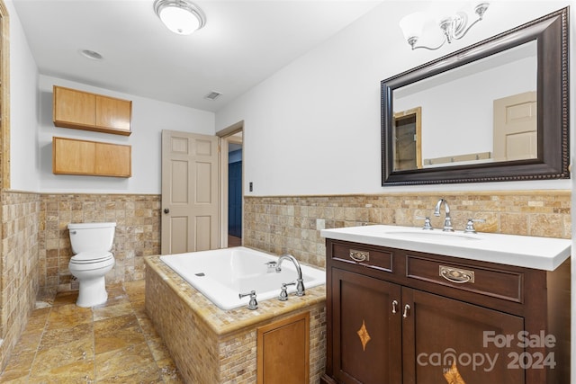 bathroom with vanity, a bathtub, toilet, and tile walls