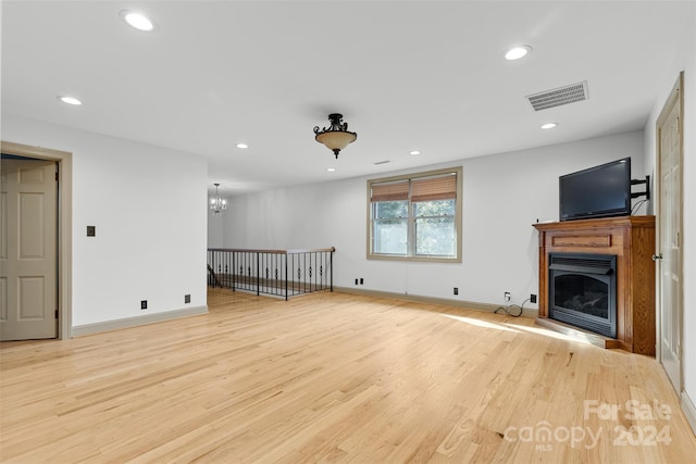 unfurnished living room featuring a chandelier and light hardwood / wood-style flooring