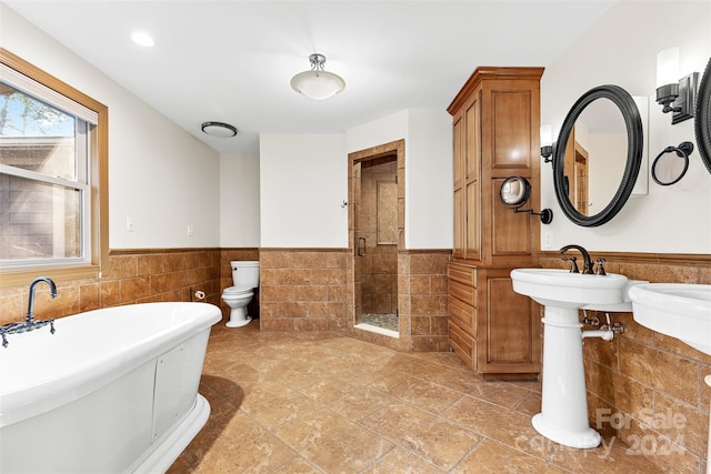 bathroom with tile patterned flooring, toilet, tile walls, and independent shower and bath