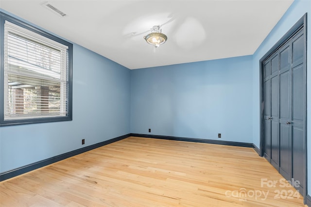 unfurnished bedroom with light wood-type flooring and a closet