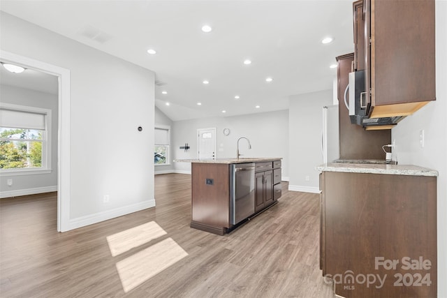 kitchen with light stone countertops, stainless steel appliances, light hardwood / wood-style floors, lofted ceiling, and a kitchen island with sink