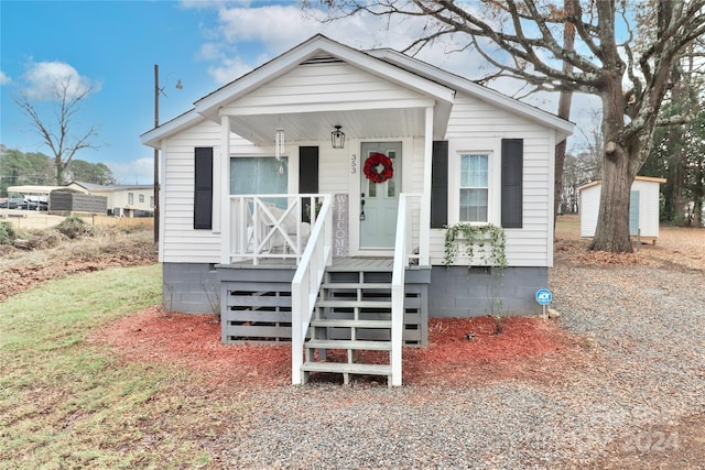 bungalow-style house featuring covered porch and a storage shed