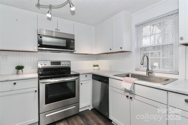 kitchen featuring sink, dark wood-type flooring, white cabinetry, stainless steel appliances, and light stone countertops