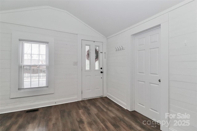 foyer entrance featuring vaulted ceiling, dark wood-type flooring, ornamental molding, and wood walls