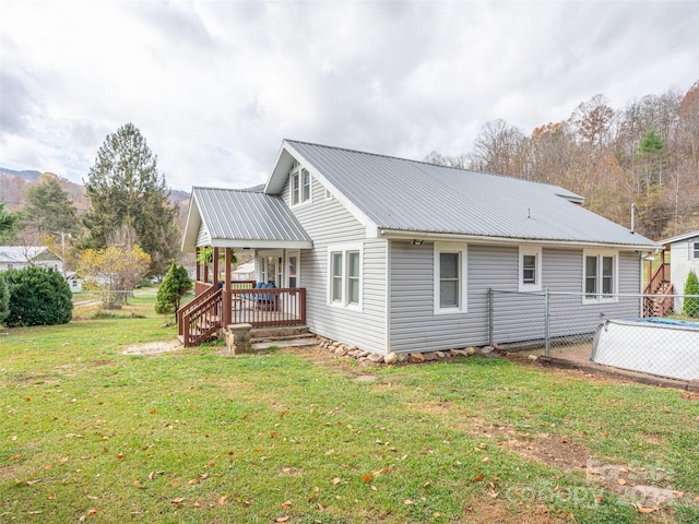 rear view of house with a lawn and a porch