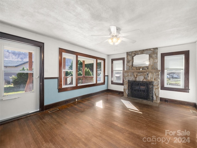 unfurnished living room with a fireplace, a textured ceiling, dark hardwood / wood-style floors, and ceiling fan