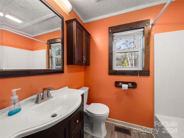 bathroom with hardwood / wood-style flooring, vanity, toilet, and a textured ceiling